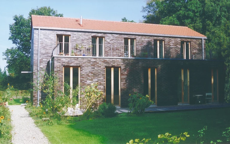 Neubau Haus A in Edewecht Ansicht vom Garten mit Eingang, Dachterrasse und Wittmunder-Klinker-Fassade.