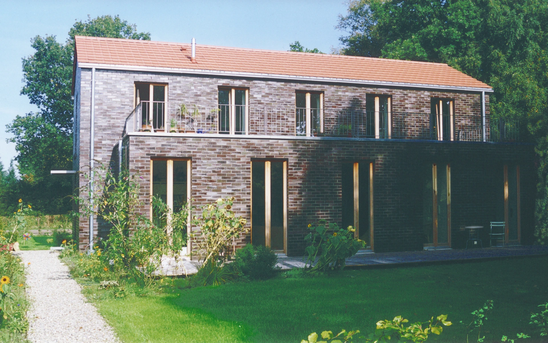 Neubau Haus A in Edewecht Ansicht vom Garten mit Eingang, Dachterrasse und Wittmunder-Klinker-Fassade.