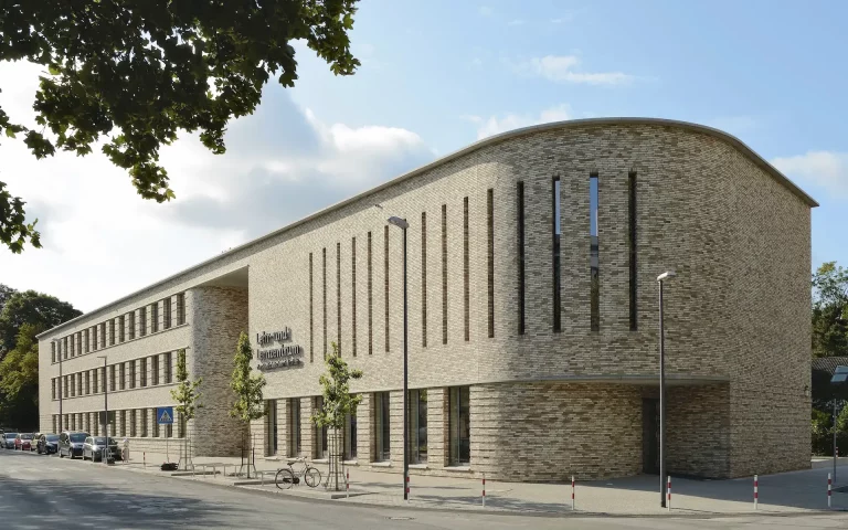 Neubau Lehr- und Lernzentrum des Universitätsklinikums Essen Straßenansicht mit langgestrecktem Backsteinbaukörper und gerundeter Fassade im Bereich des Hörsaals.