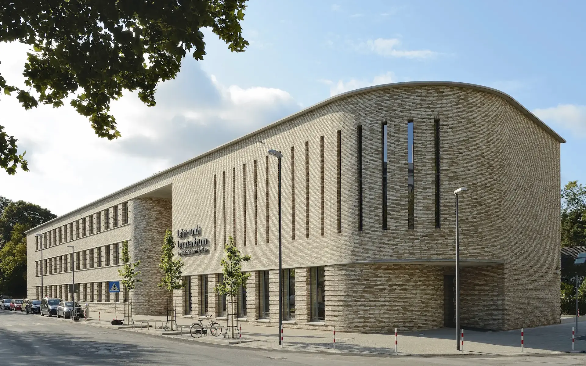 Neubau Lehr- und Lernzentrum des Universitätsklinikums Essen Straßenansicht mit langgestrecktem Backsteinbaukörper und gerundeter Fassade im Bereich des Hörsaals.