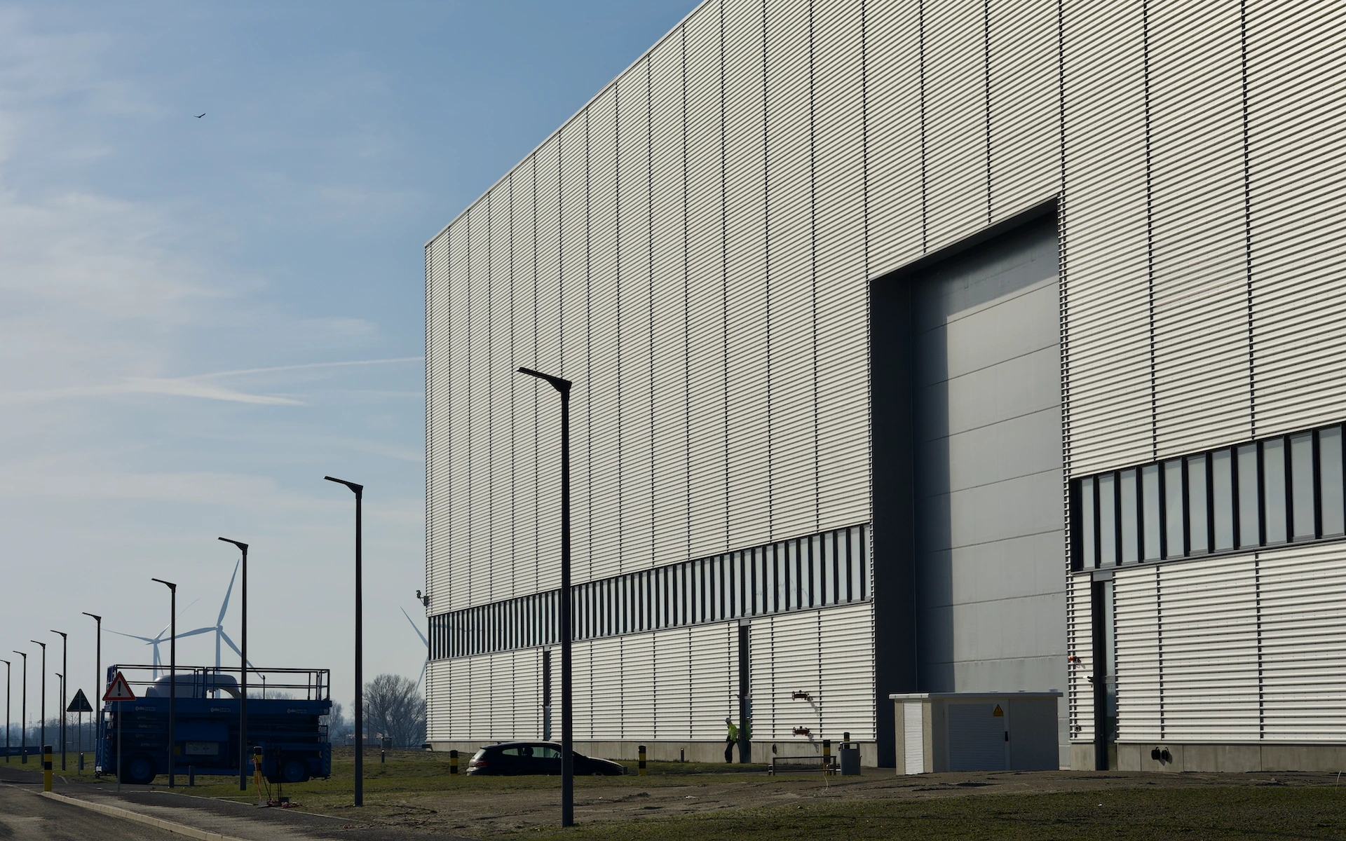 Neubau Siemens Windturbinen Fabrik in Cuxhaven als Außenaufnahme hinterlüfteter Fassade, großem Seitentor, Schwerlastumfahr und technischer Gebäudeausrüstung.