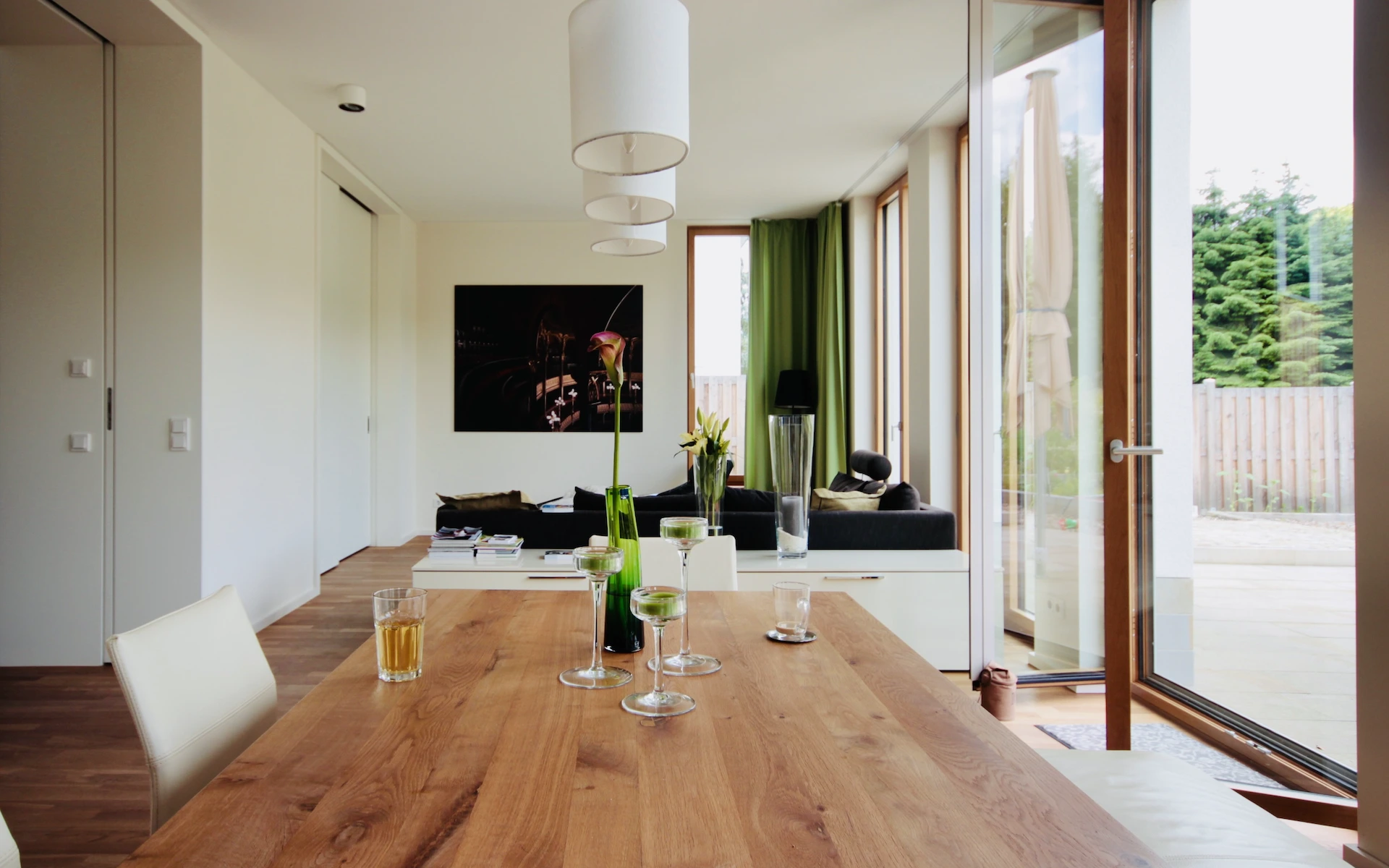 Neubau Haus D in Bochum Wohnzimmer mit französischen Fenstern, raumhohen Schiebetüren und großformatigen Parkettdielen.