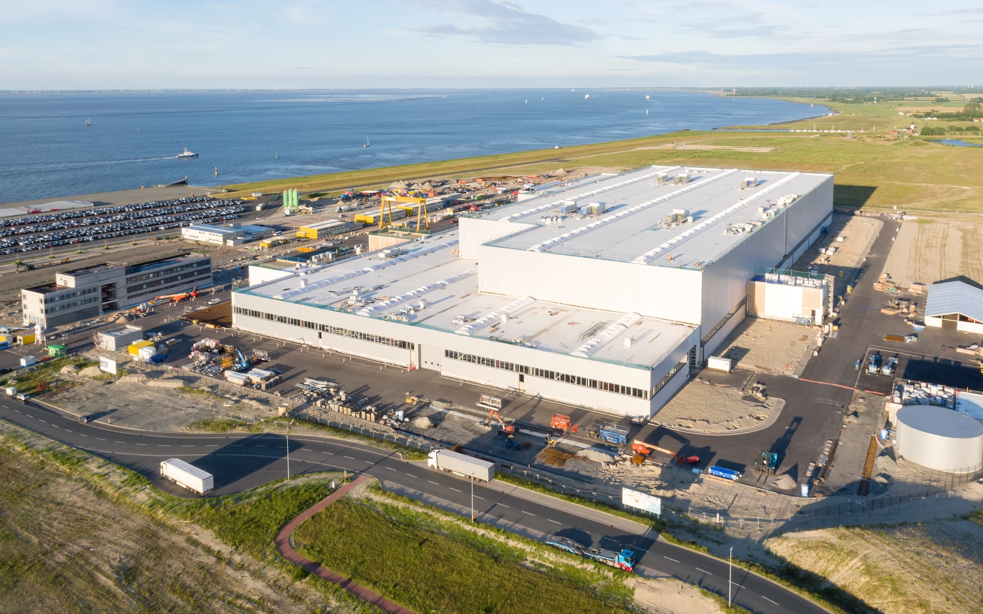 Neubau Siemens Windturbinen Fabrik in Cuxhaven als Vogelperspektive mit Büro, Pforte, Hochregallager, Technikgebäude, Schleusen und bis zu 32m hoher Dachlandschaft.