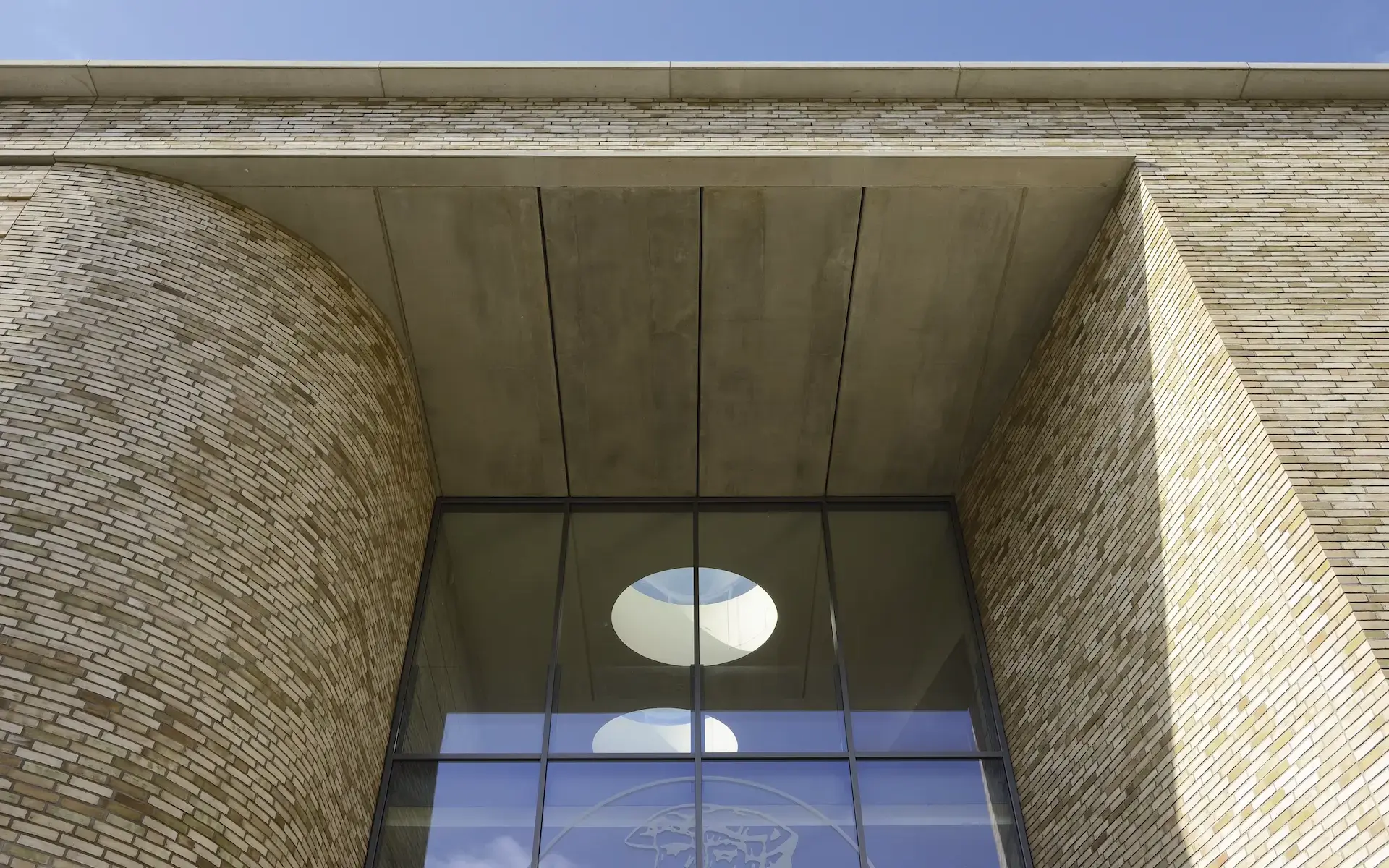 Neubau Lehr- und Lernzentrum des Universitätsklinikums Essen Detail der Eingangsfassade mit einer Pfosten-Riegelkonstruktion, wie sie sich in die Runde und orthogonal zulaufende Backsteinfassade einfügt.