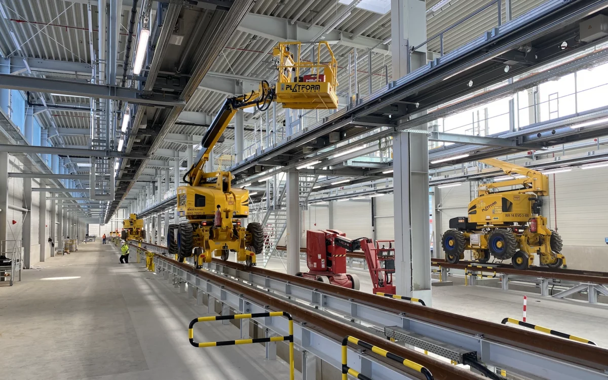 Neubau und Erweiterung Zugbildungshalle 3 Wegberg Innenraum mit Blick auf Grubenausgang, Dacharbeitsbühnen, Treppenaufgängen, aufgeständerte Gleisen und 2-Wege-Arbeitsbühnen.