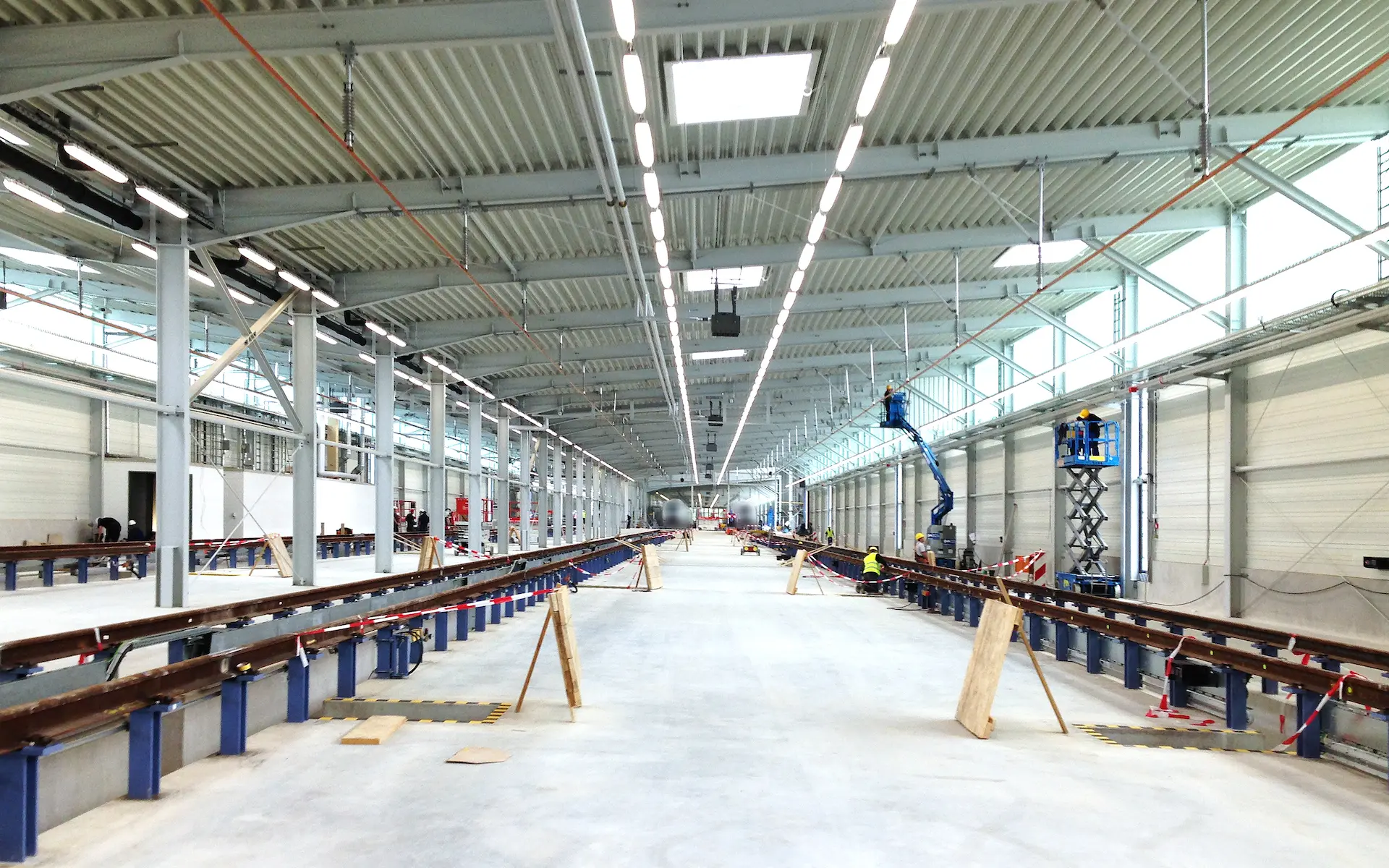 Erweiterung Siemens Zugbildungshalle 2 Innenraum mit Gleisgruben, aufgeständerten Gleisen, Fahrdraht und Lichtband.