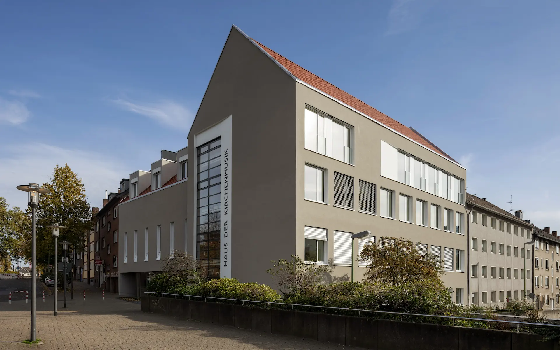 Umbau Haus der Kirchenmusik Essen Eckperspektive mit neuer Giebelfront, Sonnenschutz, Stadtraum, Sonderputz und geschlossenem Blockrand.