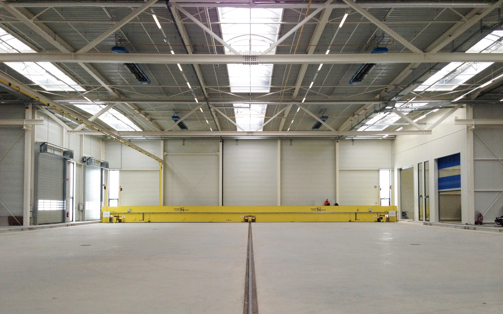 Neubau Siemens Multifunktionshalle Wegberg Innenraum mit Schiebebühne, filigranem Stahltragwerk, Spongejet Kabinen, Oberlichtbändern und Türen mit Oberlichten.