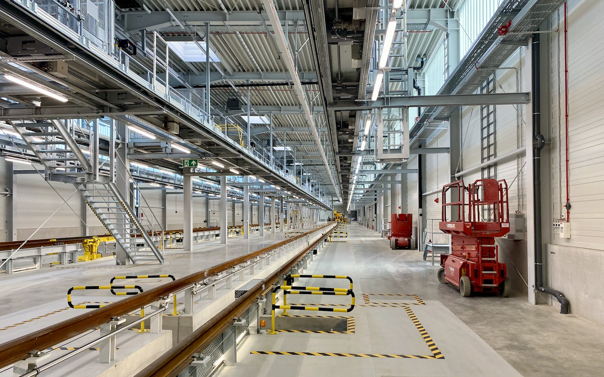 Neubau und Erweiterung Zugbildungshalle 3 Wegberg Innenraum neben der Gleisgrube mit Blick auf Grubenausgang, Dacharbeitsbühnen, Treppenaufgänge und aufgeständerte Gleise.
