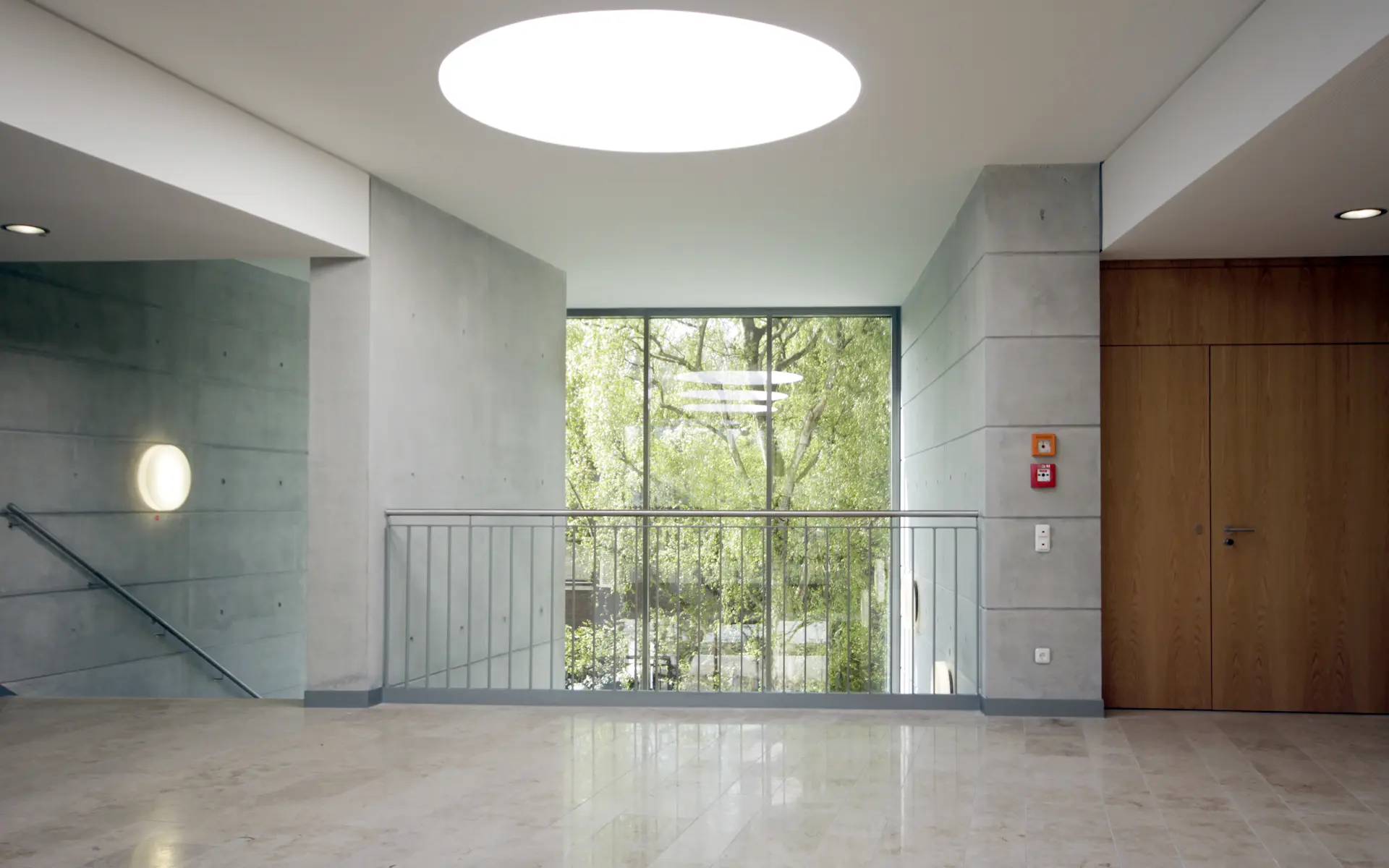 Neubau Lehr- und Lernzentrum des Universitätsklinikums Essen Foyer im obersten Geschoss mit Sichtbetonwänden, Holzpaneelen, Oberlicht und Brüstung.