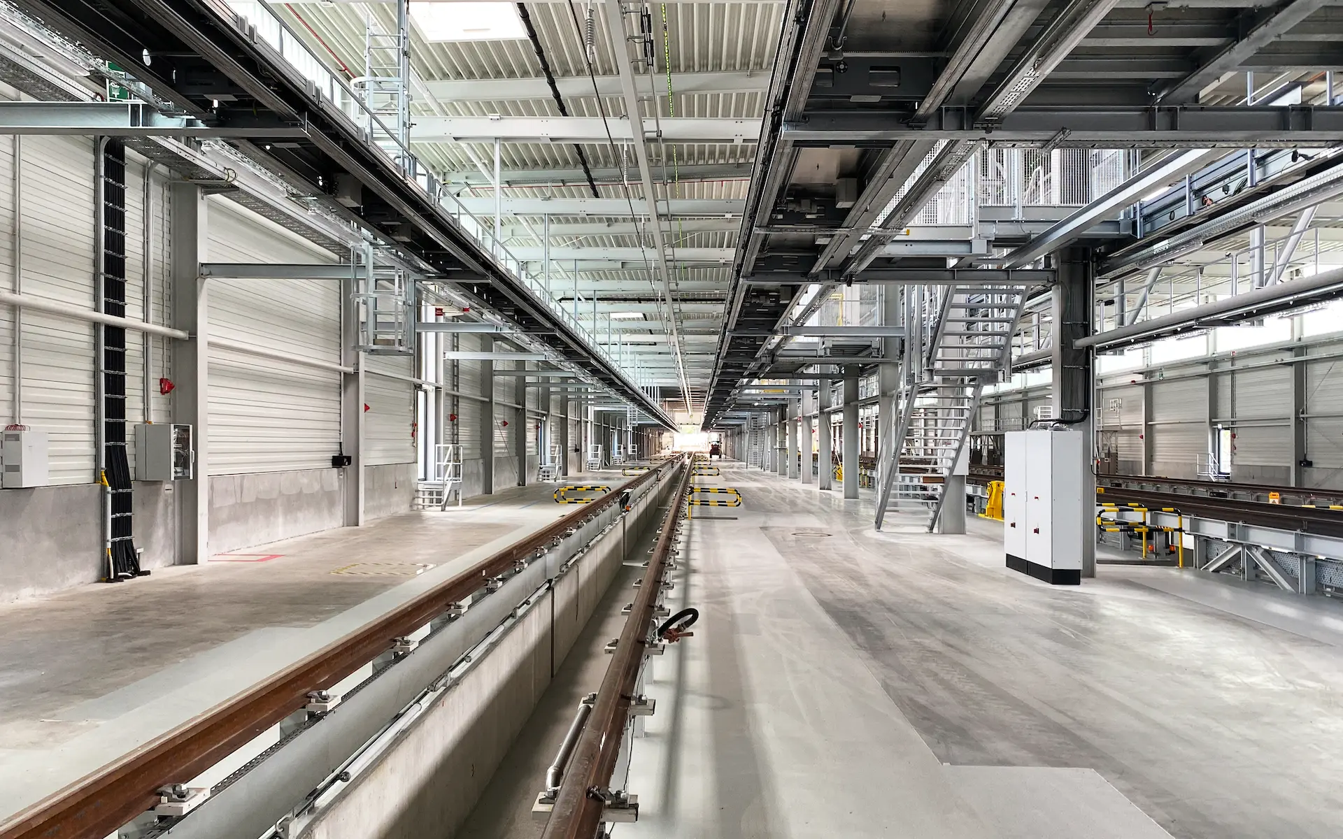 Neubau und Erweiterung Zugbildungshalle 3 Wegberg Innenraum der Zugbildungshalle in der Gleissachse mit Blick längs der Grube zum Halleneingang, im Vordergrund nivellierter Industrieboden, an der Decke der Fahrdraht.