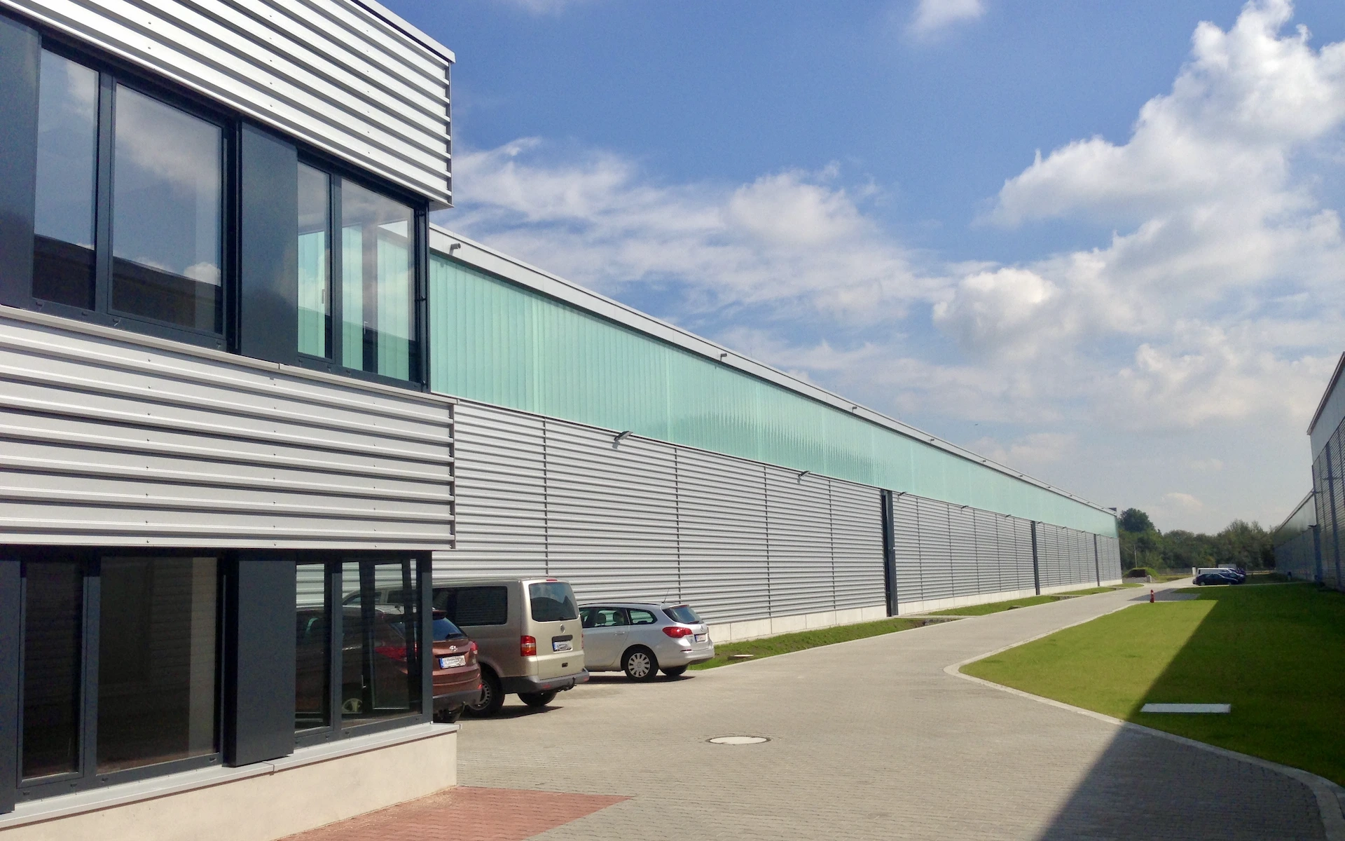 Neubau und Erweiterung Zugbildungshalle 3 Wegberg Ansicht des 1. Bauabschnitts der Zugbildungs-Halle mit Blick auf die Längsseite, Lichtband, gegliederter Fassade, Betonsockel, im Vordergrund der Bürotrakt.