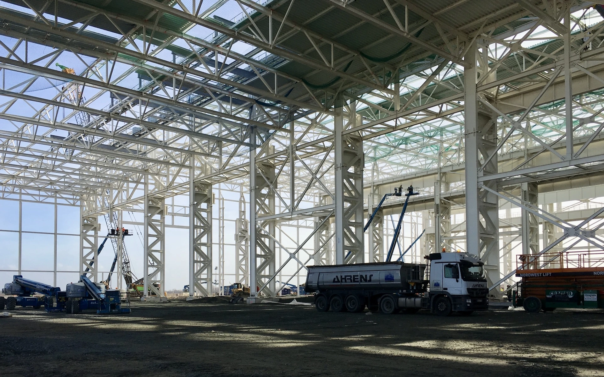 Baustelle Neubau Siemens Windturbinen Fabrik in Cuxhaven mit Fachwerk einer Produktionslinie, Trapezeindeckungen und Baustellenlogistik.