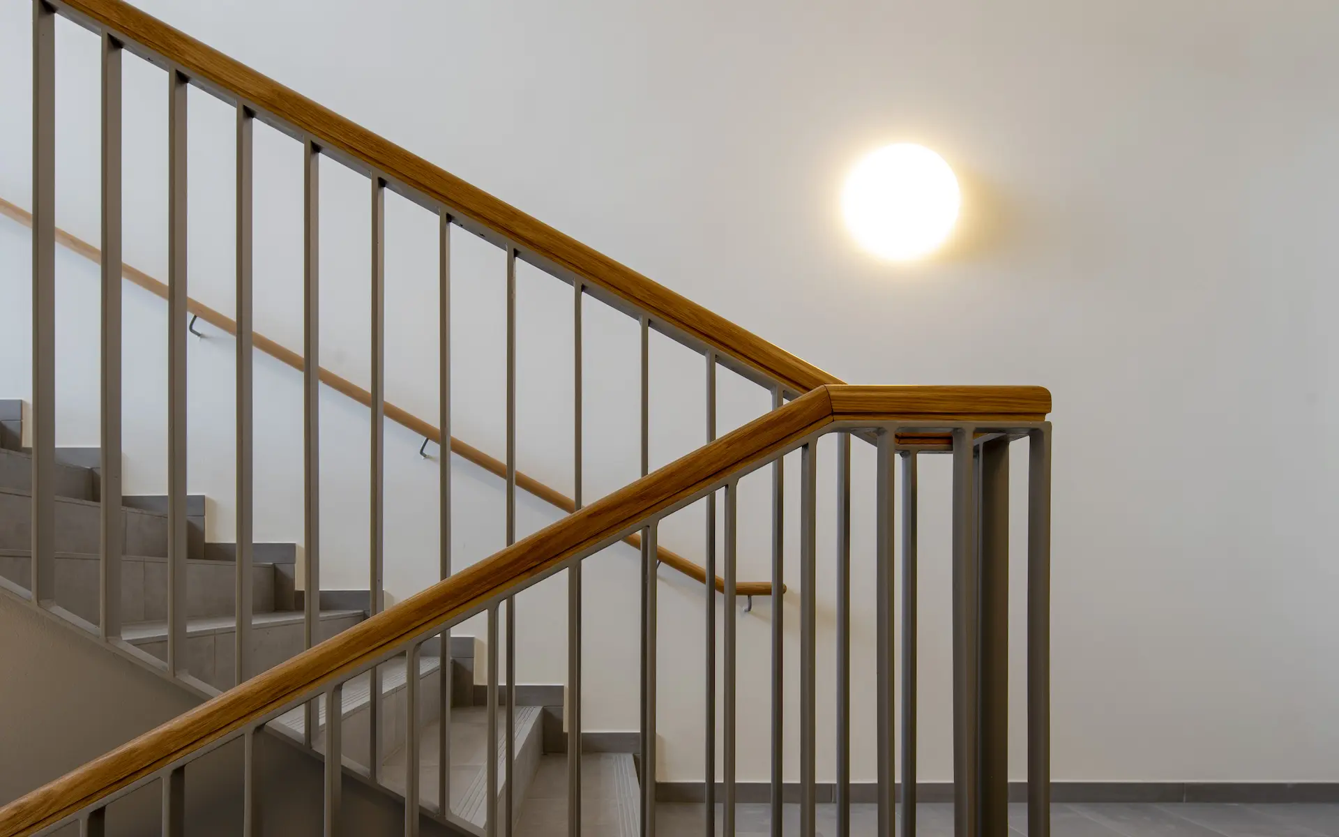 Umbau Haus der Kirchenmusik Essen Innenraum Detail mit Treppenhaus, kunstvoll verkröpften Handlauf der Stahlgeländer-Harfe, unterschiedliche Treppen-Podeste und koordinierte Leuchten.
